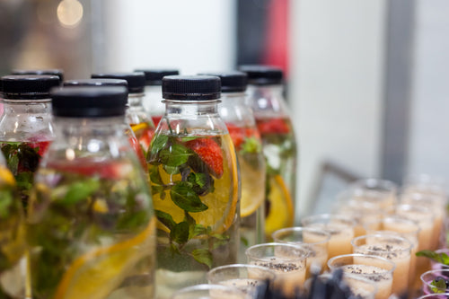 Clear bottles with black caps filled with strawberry, lemon and mint infused water